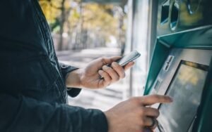 manos usando un telefono movil en un cajero